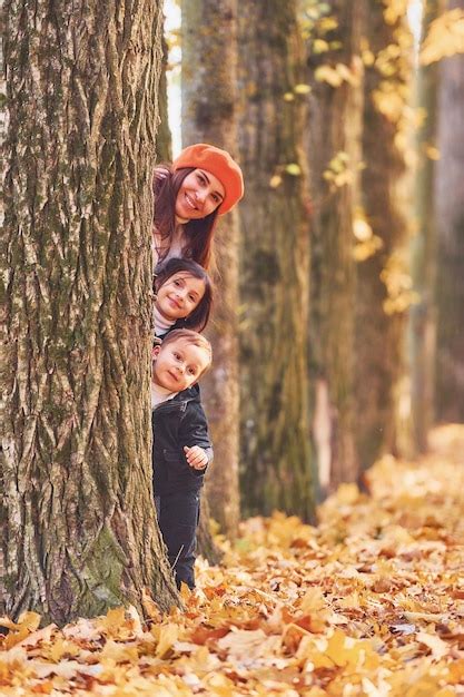 Escondiéndose detrás del árbol la madre con su pequeño hijo y su hija