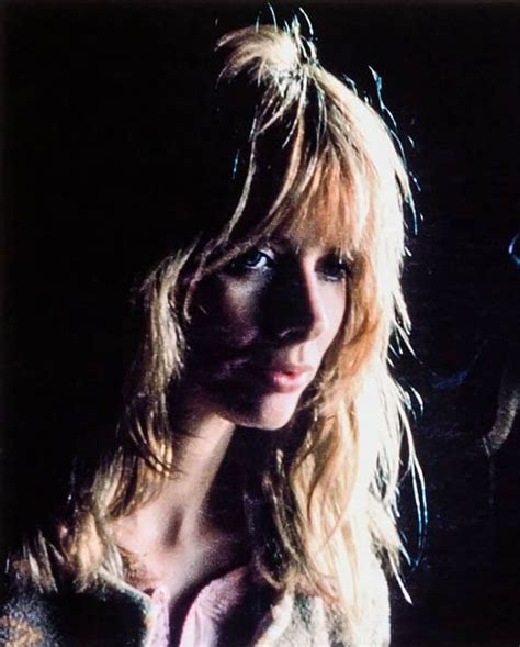 a woman with long blonde hair standing in the dark