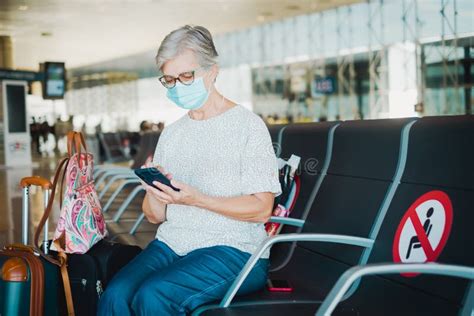 Traveler Mature Woman Sitting In Airport With Luggages Using Mobile