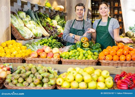 Vendedores De Frutas Y Verduras De Ambos Sexos Cerca De Puestos En El Mercado De Frutas Imagen