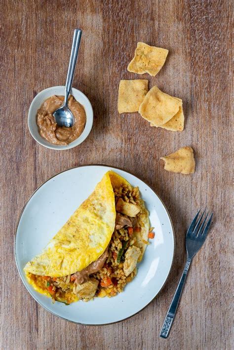 An Omelet On A White Plate Next To Some Tortilla Chips And Salsa