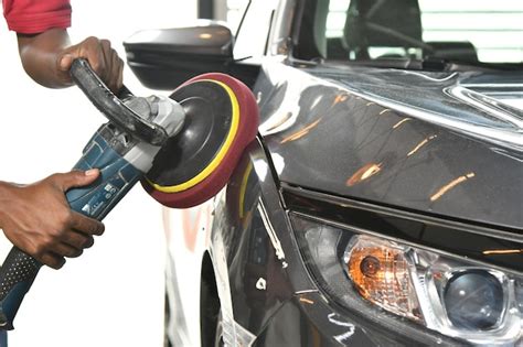 Premium Photo | A man is using a paint sprayer to spray paint a car.