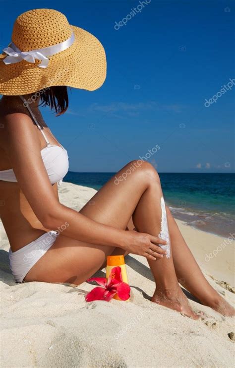 Woman Applying Sunscreen On The Beach Stock Photo Serrnovik