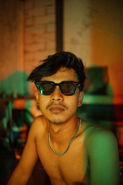 Premium Photo A Gay Man In Sunglasses And Denim Pants Sits Relaxing In A Club To Celebrate