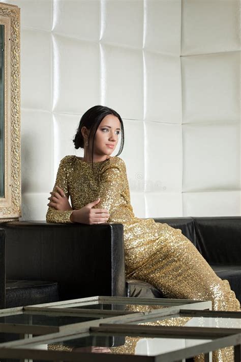 Pretty Brunette Woman In Gold Dress Posing On Sofa Stock Photo Image Of Interior Gold