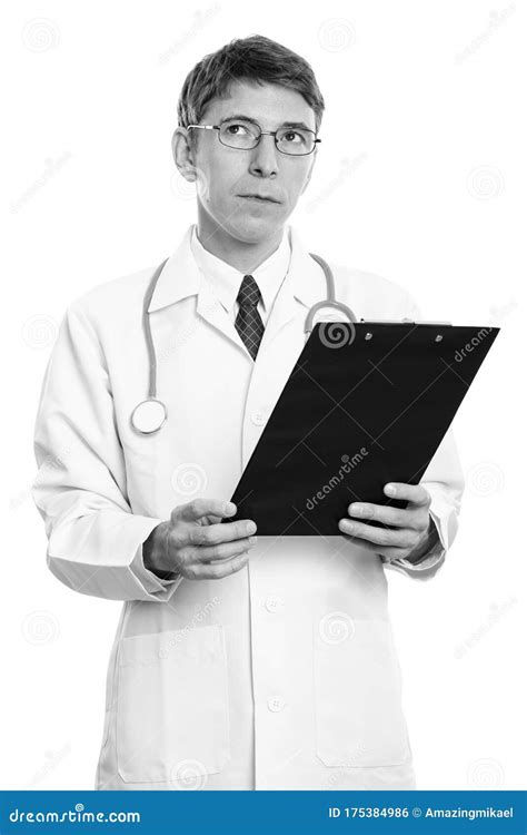 Studio Shot Of Man Doctor Holding Clipboard While Thinking Stock Photo