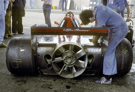 A Man Working On A Race Car With Other Men Standing Around And Looking