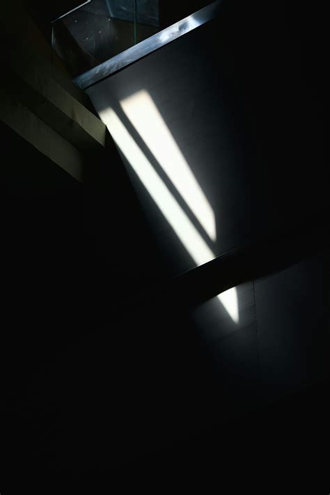 A dark room with a light coming through the window photo – Free