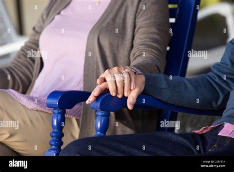 Older Couple Sitting In Rocking Chairs Detail On Holding Hands Stock