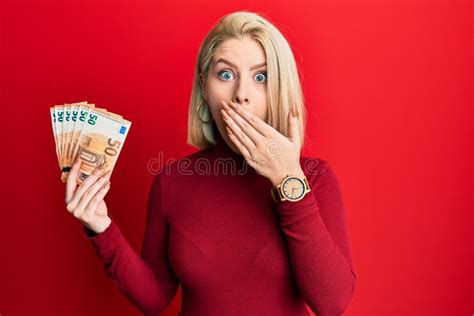 Jeune Femme Blonde Tenant Un Paquet De Billets De Euros Couvrant La Bouche Avec La Main