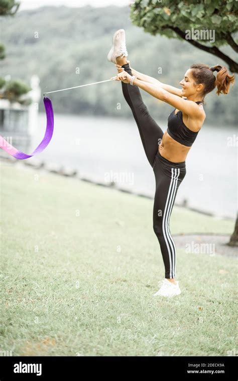 Athletic Woman Practising Rhythmic Gymnastics With A Ribbon Outdoors