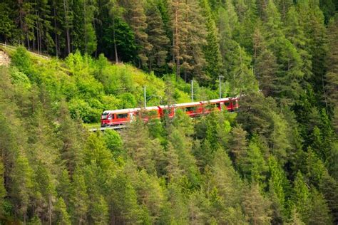 Premium Photo | Red train going in green forest in Switzerland