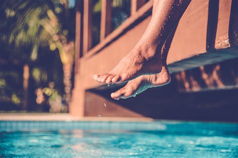 Dangling Tanned Female Legs Over Blue Tiled Summer Swimming Pool Stock