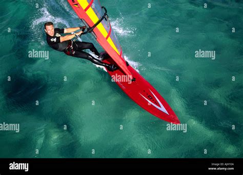 Aerial Panning View Of Smiling Windsurfer On Sailing On Clear Emerald