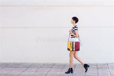 Elegante Mujer Caminando Sobre El Pavimento Con Bolsa Imagen De Archivo