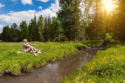 Jeune Belle Fille Blonde En Short Avec De Belles Jambes Est Assise Sur Les Rives D Un Ruisseau