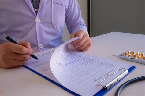 Premium Photo Midsection Of Doctor Writing On Paper At Clinic