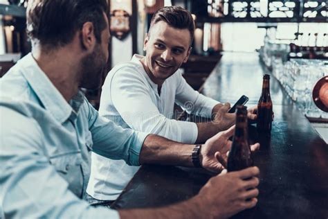 Homens De Sorriso Novos Que Bebem A Cerveja Na Barra Moderna Imagem De