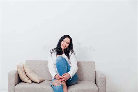Beautiful Brunette Woman Sitting On Grey Sofa In White Room Stock Photo Image Of Caucasian