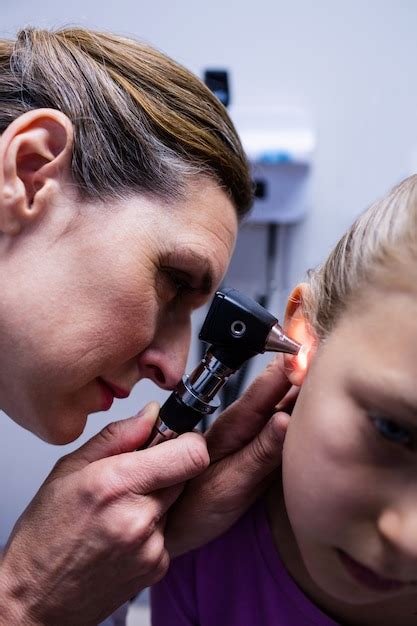 Doctora Examinando El O Do Del Paciente Con Otoscopio Foto Premium