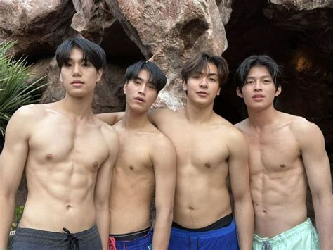 Three Men Standing Next To Each Other In Front Of Some Rocks And Plants