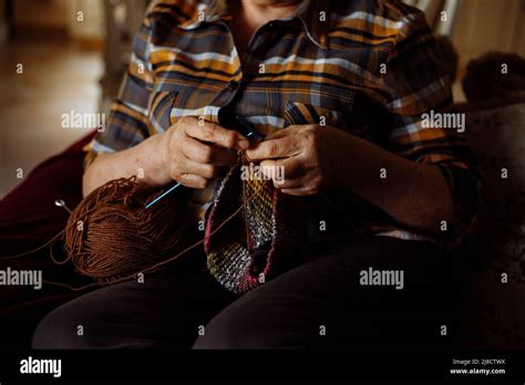 Femme mature dans les vêtements de la maison assis sur le canapé dans la salle de séjour et