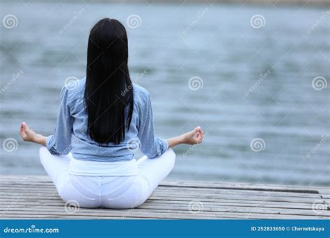 Young Woman Meditating Near River Back View Space For Text Stock