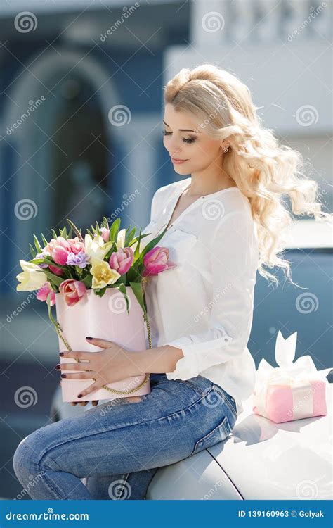 Belle Jeune Blonde Avec Les Cheveux Onduleux Dehors Avec Un Grand Bouquet Des Fleurs Sur Une Rue