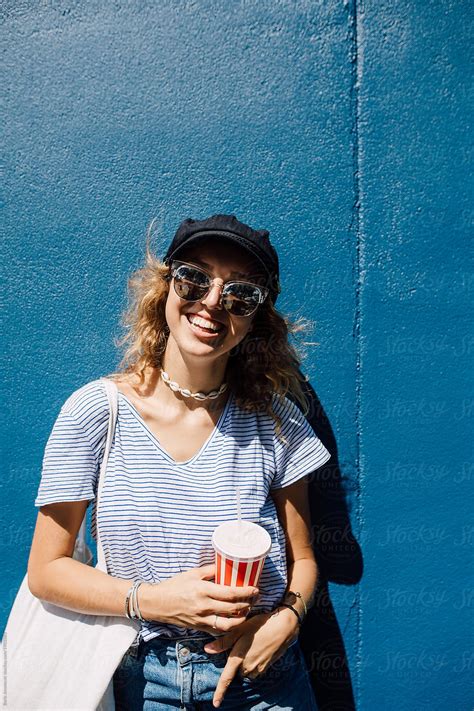 Portrait Of A Beautiful Blonde Woman Standing By The Blue Wall Background By Stocksy