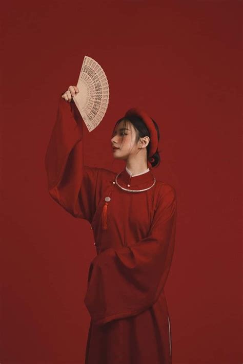 A Woman In A Red Dress Holding Up A Fan With Her Right Hand And Looking