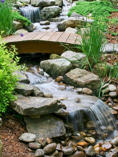 a wooden bridge over a small stream with rocks and water flowing down ...