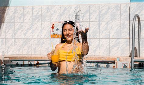 Mujer con bikini caliente atractiva sonriente sosteniendo un vaso en su mano durante un baño en