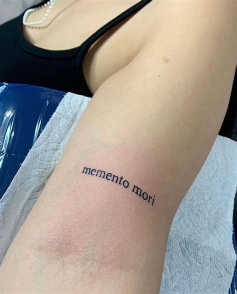 A Woman With A Tattoo On Her Arm That Reads Mementoo Moii