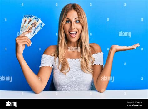 Schöne blonde junge Frau hält schweizer Franken Banknoten feiern Leistung mit glücklichen