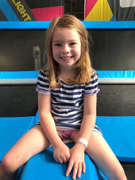 Premium Photo Portrait Of Smiling Girl Sitting On Trampoline