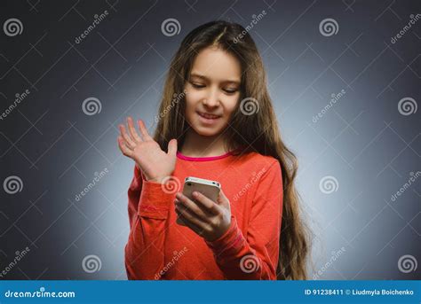 Menina Bonito Que Fala No Telefone De Pilha Isolado No Cinza Imagem De