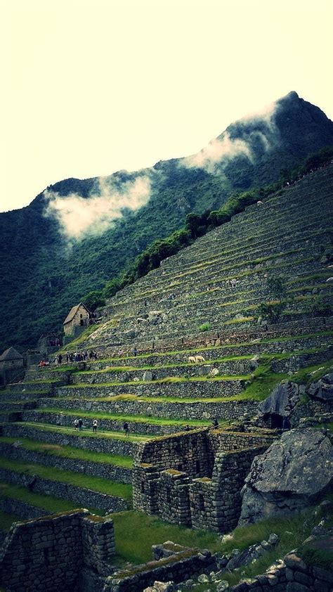 An Old Stone Structure Sitting On Top Of A Lush Green Hillside Next To