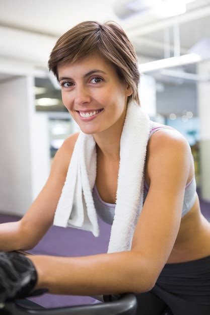 Ajuste la mujer sonriente que se resuelve en la bicicleta estática