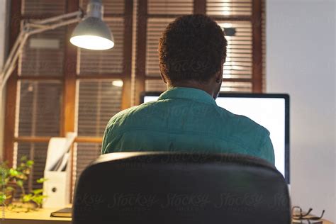 Back View Of Black Man Using Computer At Late Afternoon On His Desktop