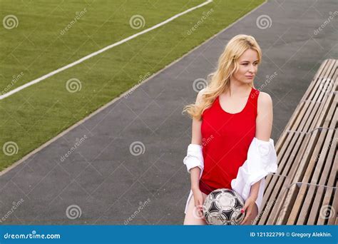 Blonde With A Ball On The Football Field In Red Uniform Stock Image