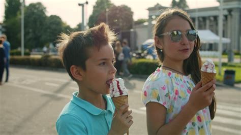 Linda hermana y hermano comiendo helado niños sonrientes caminando en