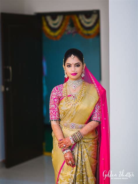 A Woman In A Yellow And Pink Sari Posing For The Camera With Her Hands