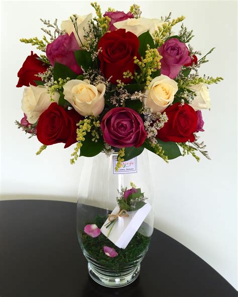 A Vase Filled With Red White And Pink Roses Sitting On Top Of A Table