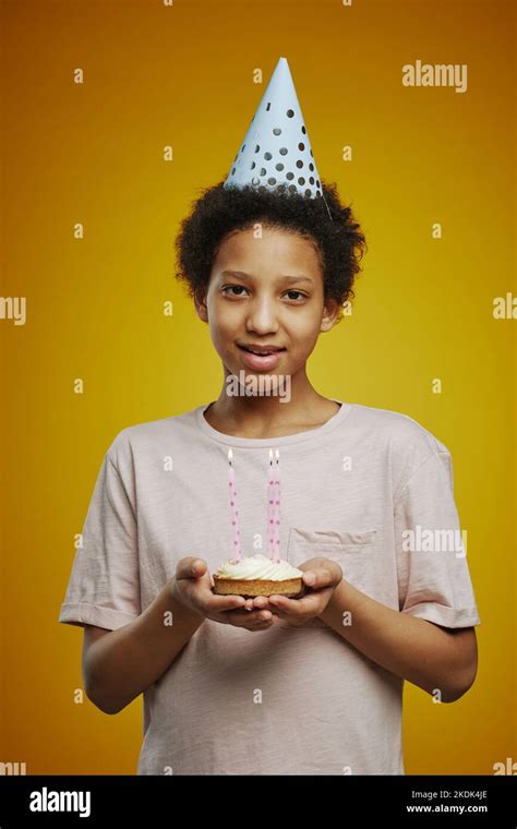 Smiling Adolescent Girl In White T Shirt And Cap Holding Small Birthday Cake With Burning