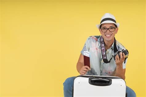 Joven turista con sombrero sentado mirando a la cámara sonriendo con su