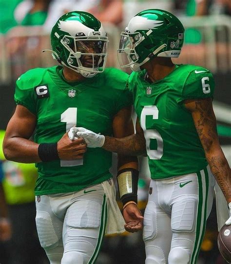 Two Football Players In Green Uniforms Standing Next To Each Other