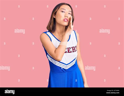 Young Beautiful Chinese Girl Wearing Cheerleader Uniform Hand On Mouth