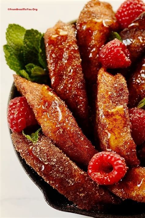 A Bowl Filled With French Toast And Raspberries On Top Of A White Table