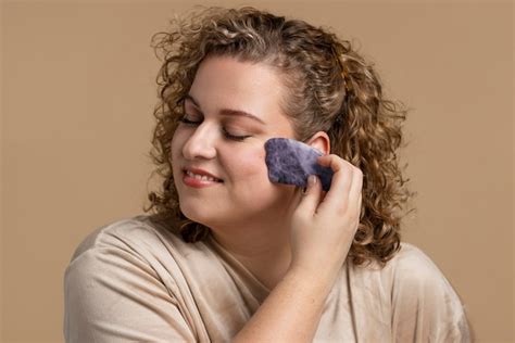 Mujer Masajeando La Cara Con Gua Sha Tiro Medio Foto Gratis