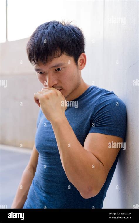 Portrait Of Young Asian Man Thinking Against The Wall Outdoors Stock